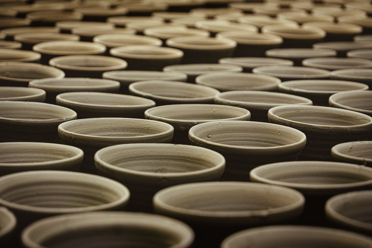 hero-img-01 Multiple handcrafted clay pots aligned in a traditional pottery workshop.